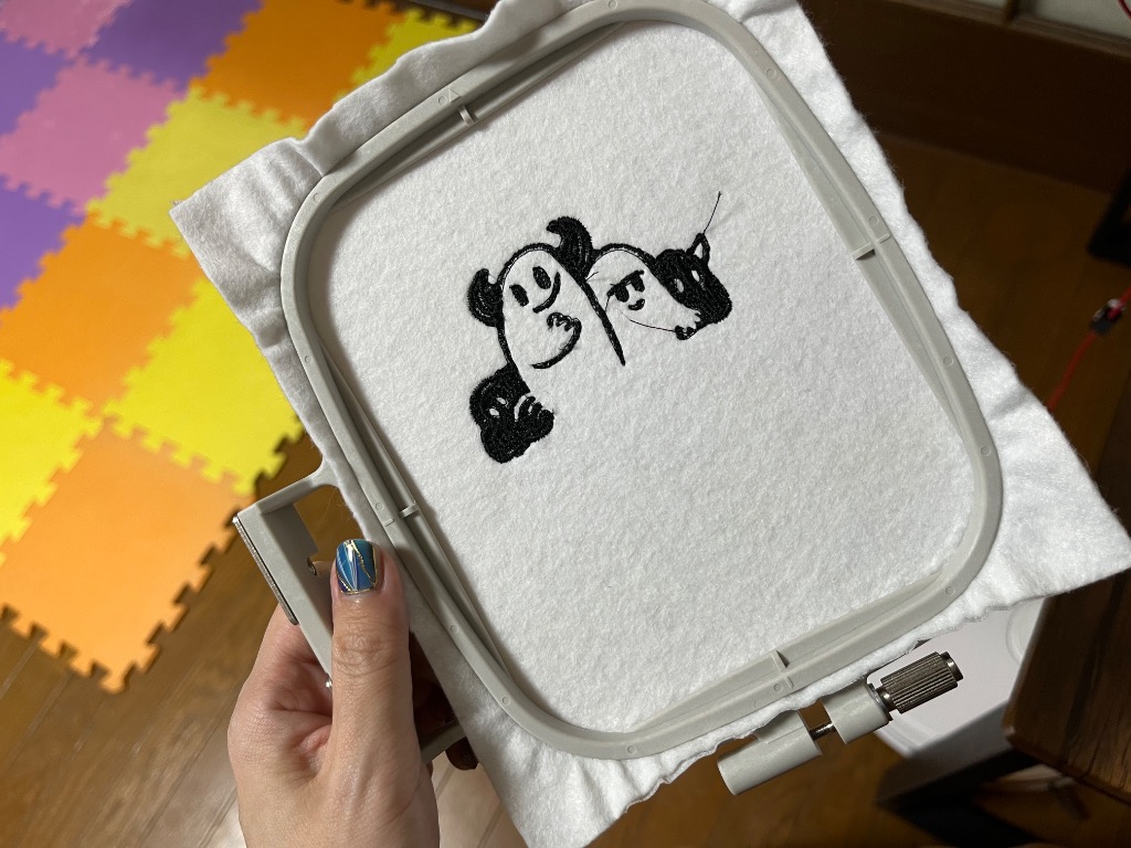 白いフェルト生地の刺繍枠に、黒糸でキャラクターが縫われた刺繍の完成品